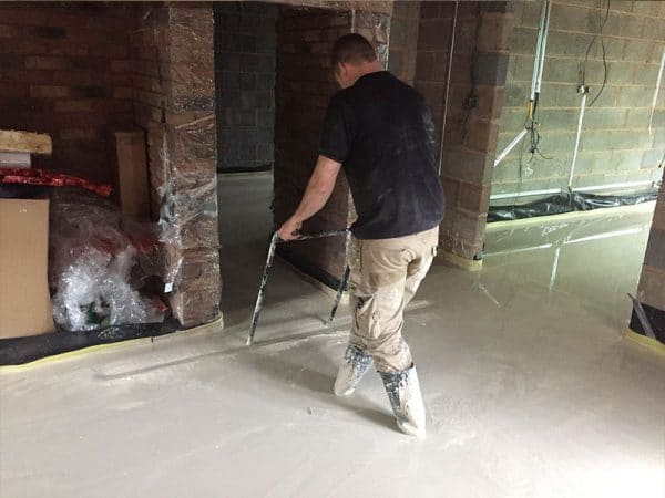 Thin floor screed taking place by one gentleman - smoothing process for floor screeding extensions