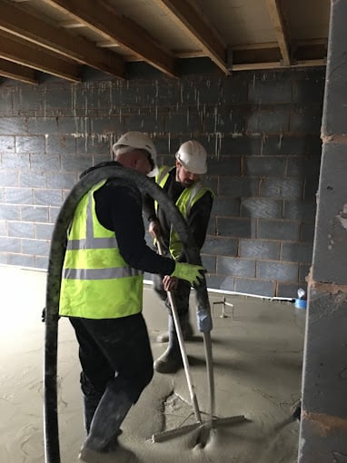 Liquid screed being pumped by two GM Floor Screeds workers: floor screeding services in Manchester
